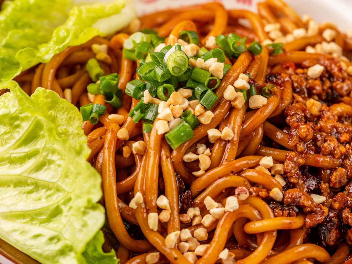 Chinese Hot and Dry Noodles mit Salatblatt in einer braunen Schale. Draufsicht.