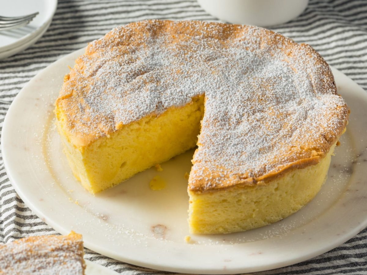 Japanischer Soufflé Käsekuchen mit Puderzucker angeschnitten auf einem weißen Teller.