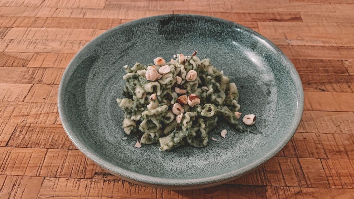 Ein Teller Pasta mit Brokkoli-Grünkohl-Sauce und gehackten Haselnüssen bestreut.