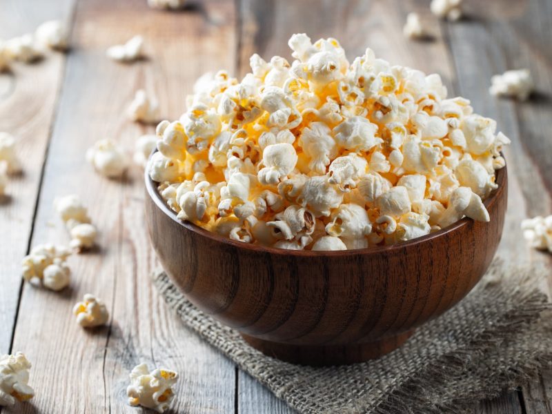 Eine braune Schale mit dem Popcorn auf einem dunklen Holztisch.