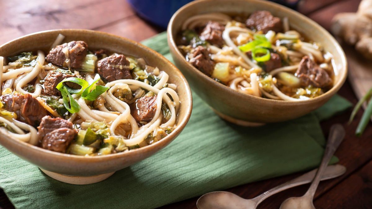 Zwei Schüsseln mit der Nudelsuppe auf einem grünen Tuch.