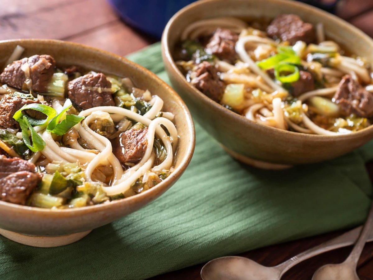 Zwei Schüsseln mit der Nudelsuppe auf einem grünen Tuch.