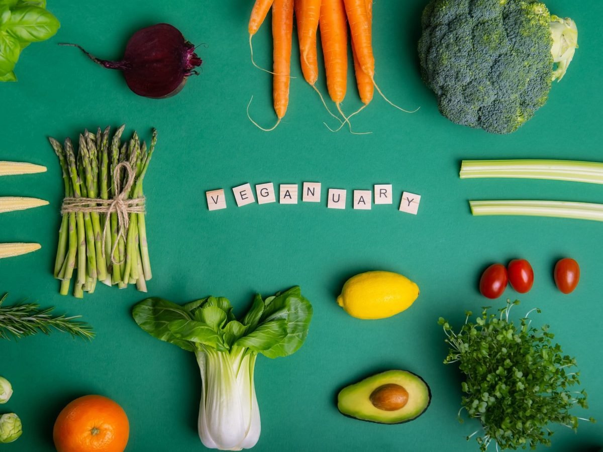 Veganuary 2023: Das Wort "Veganuary" mit Scrabble-Buchstaben gelegt, drumherum Gemüse angeordnet, alles Draufsicht.