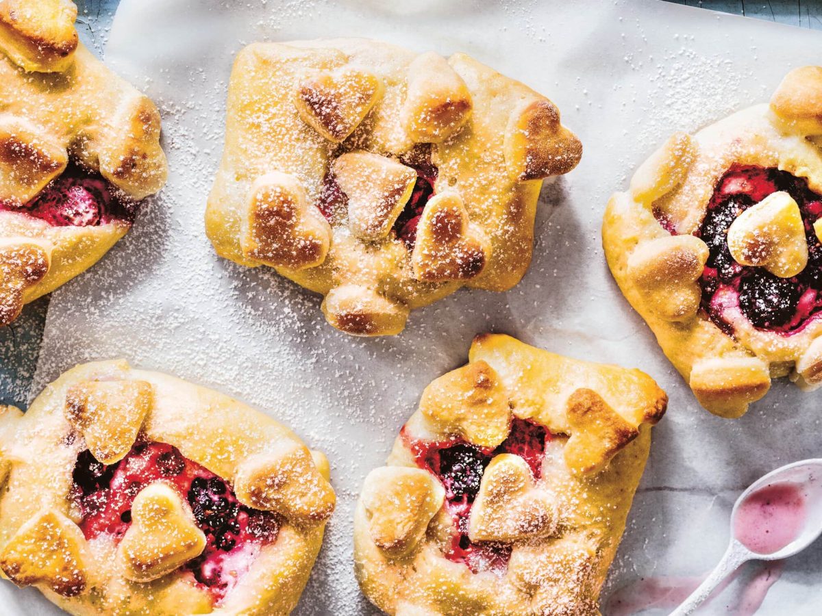 Draufsicht: Quarktaschen mit Beeren-Brandy-Creme liegen auf einem Backblech.