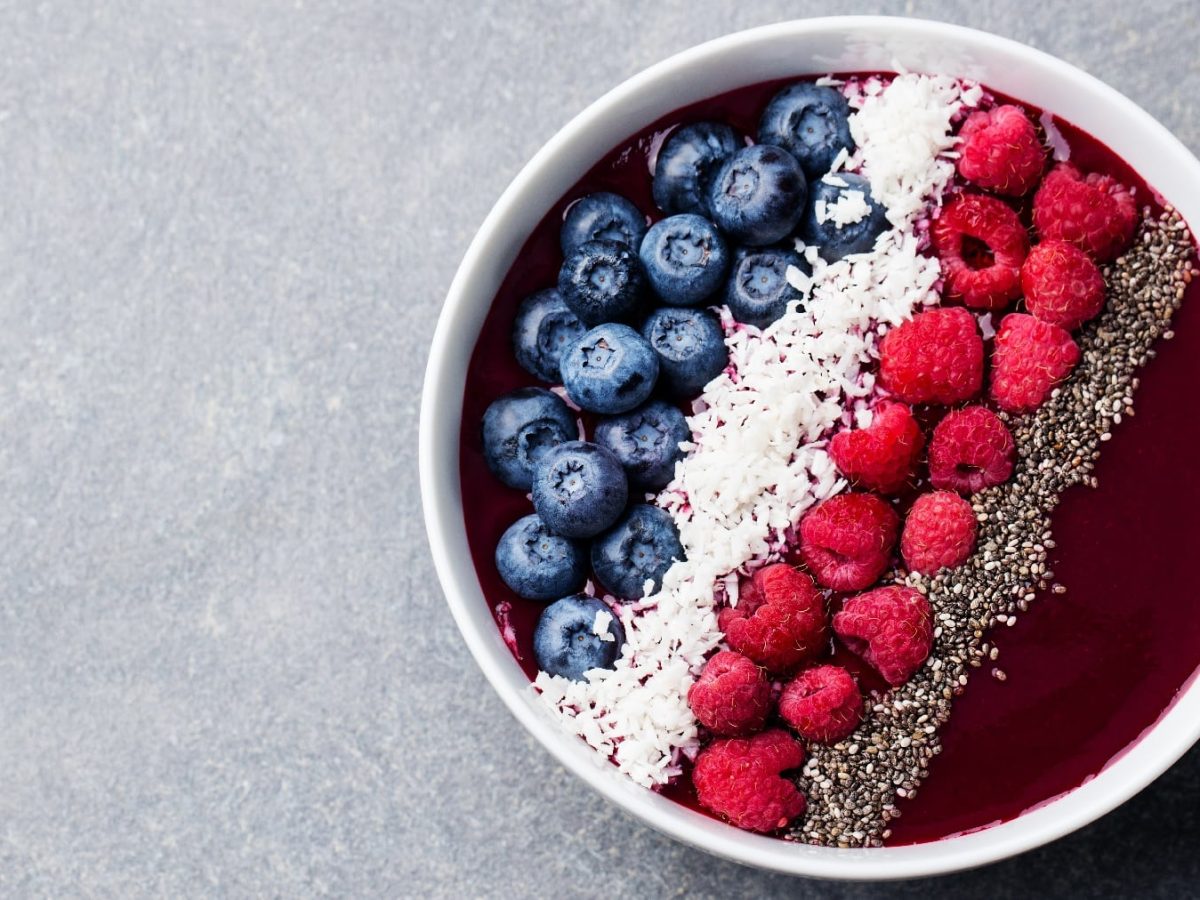 Eine weiße Schale mit der Drachenfrucht-Bowl auf einem grauen Untergrund.