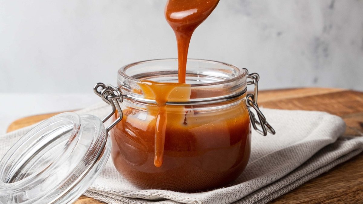 Ein Einmachglas mit Butterscotch-Sauce auf einem weißen Geschirrtuch.