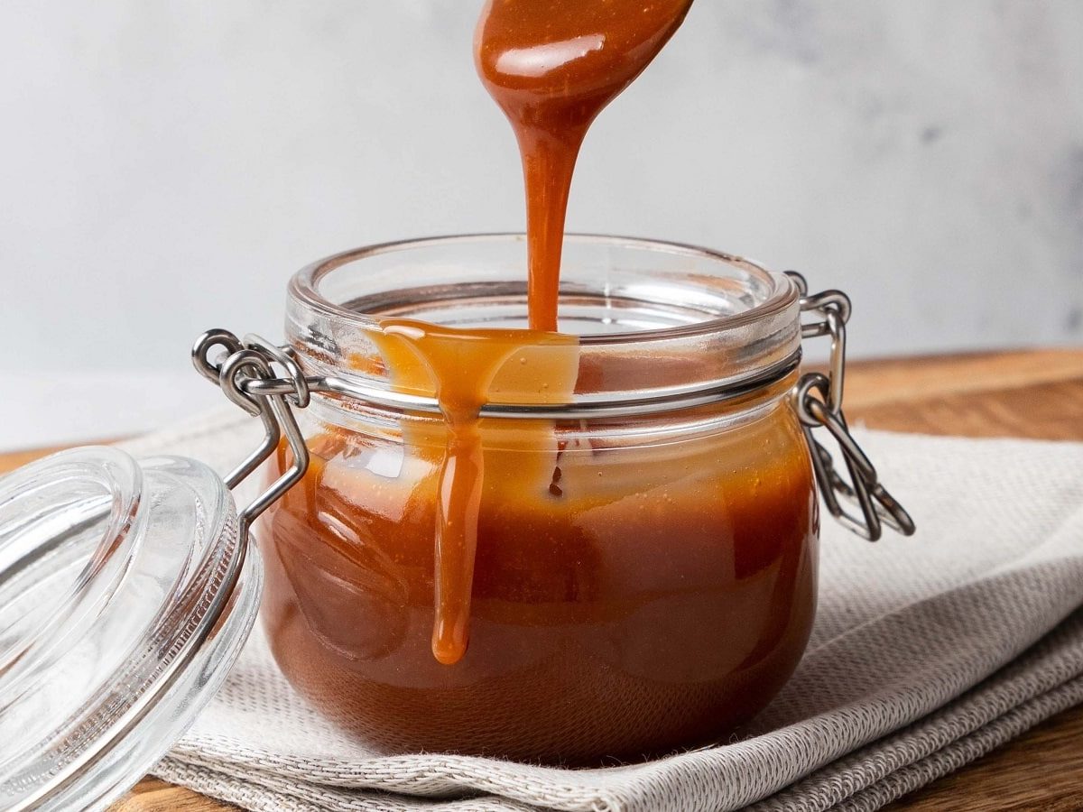 Ein Einmachglas mit Butterscotch-Sauce auf einem weißen Geschirrtuch.