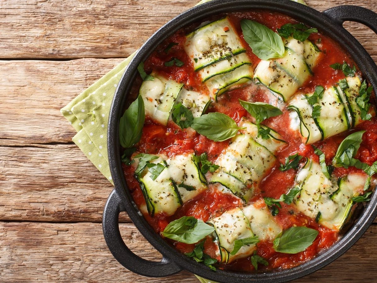 Ein schwarzer Topf mit Involtini di Zucchini auf einem Holztisch.