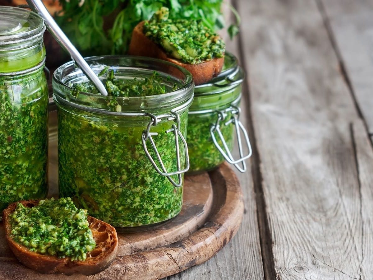 Zwei Gläser mit Koriander-Pesto auf einem Holzbrett.