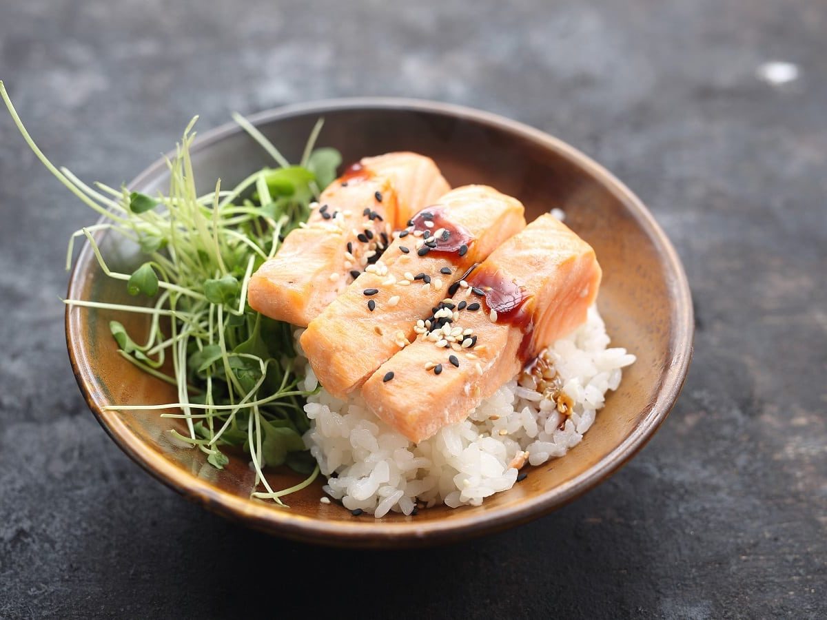 Ein Teller mit Mirin-Lachs auf Reis auf einem grauen Tisch.