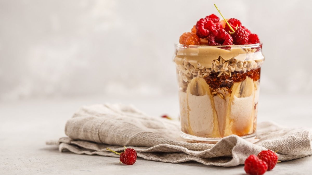 Ein Glas mit Peanutbutter & Jelly Overnight Oats auf einem grauen Tuch.