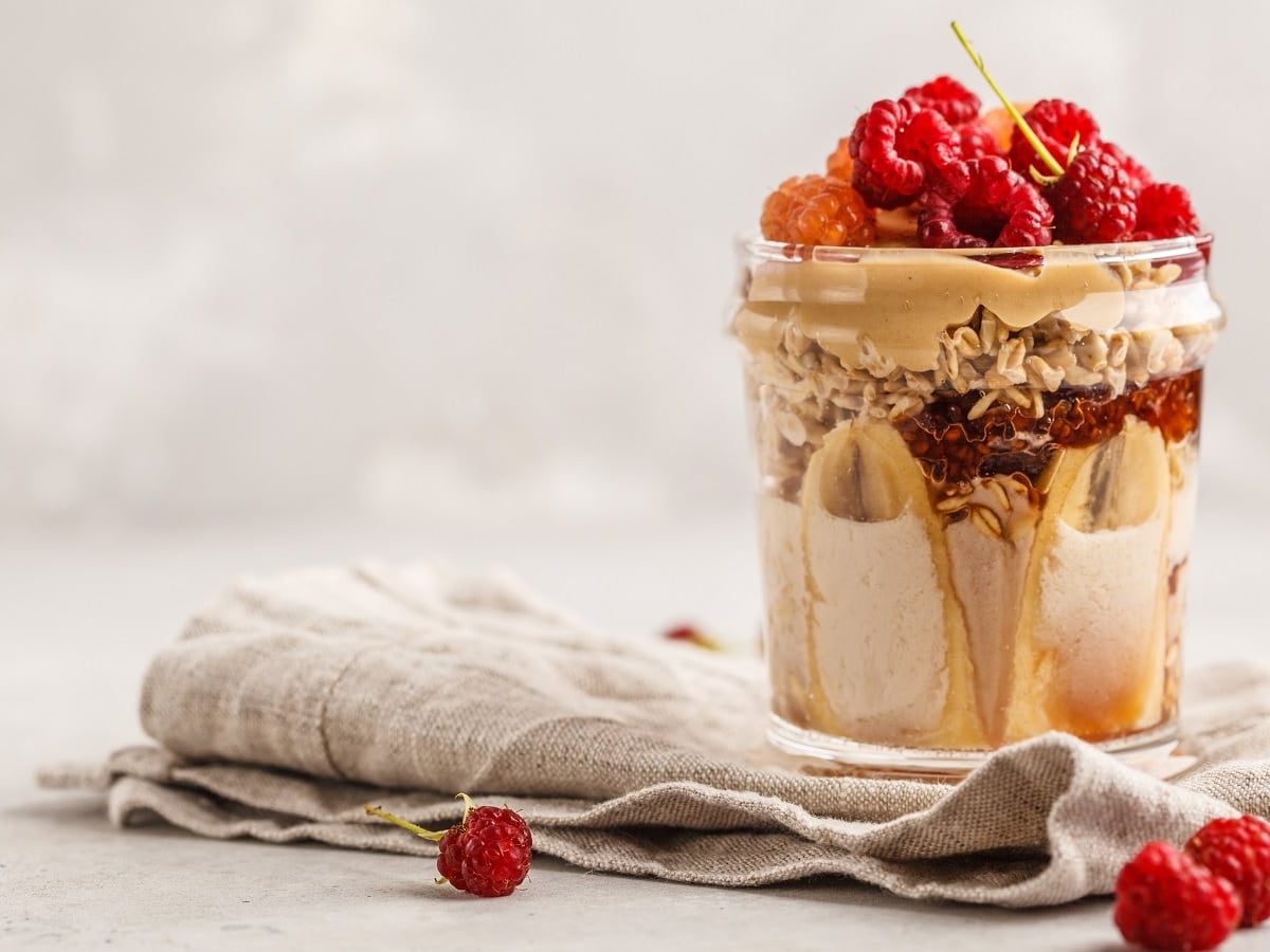 Ein Glas mit Peanutbutter & Jelly Overnight Oats auf einem grauen Tuch.