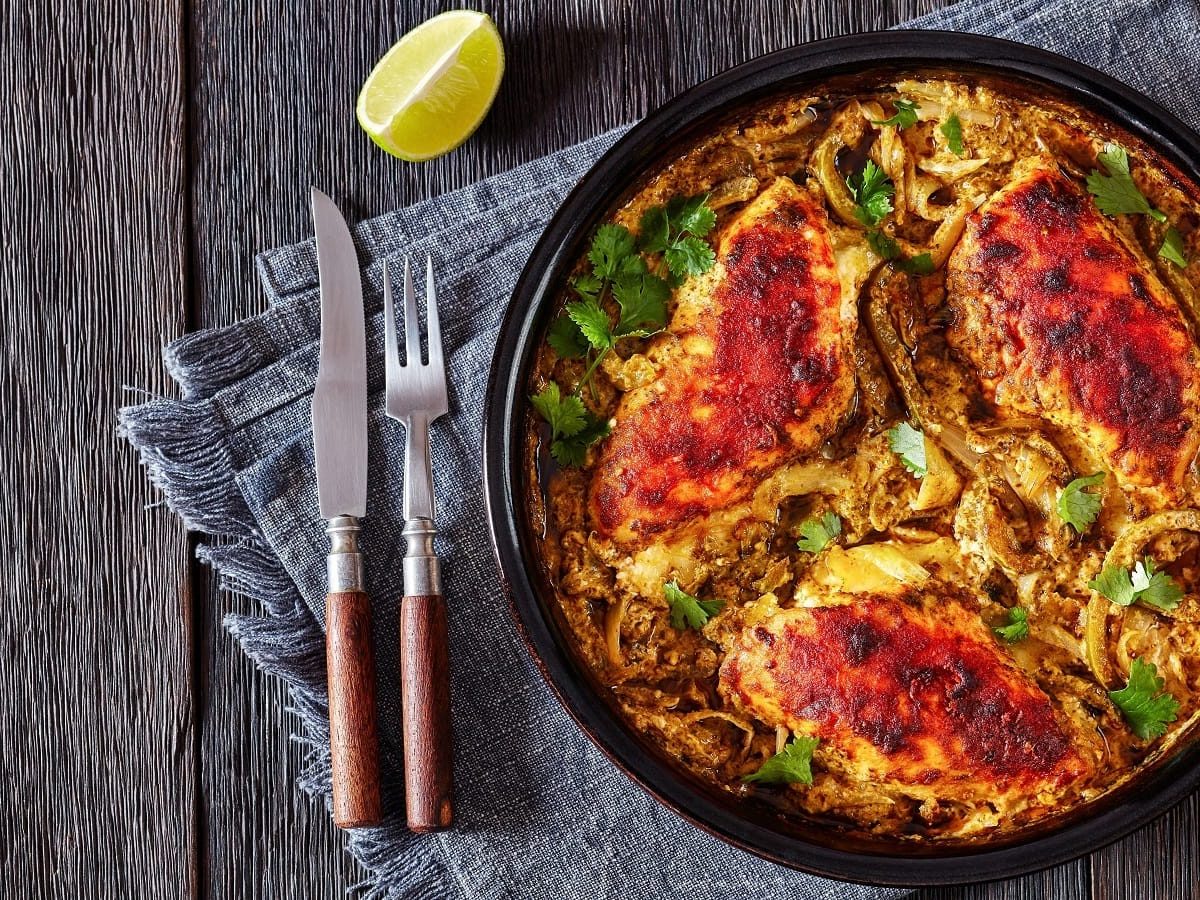 Ein Topf mit Salsa Verde Chicken auf einem blau-grauen Geschirrtuch auf einem Holztisch.