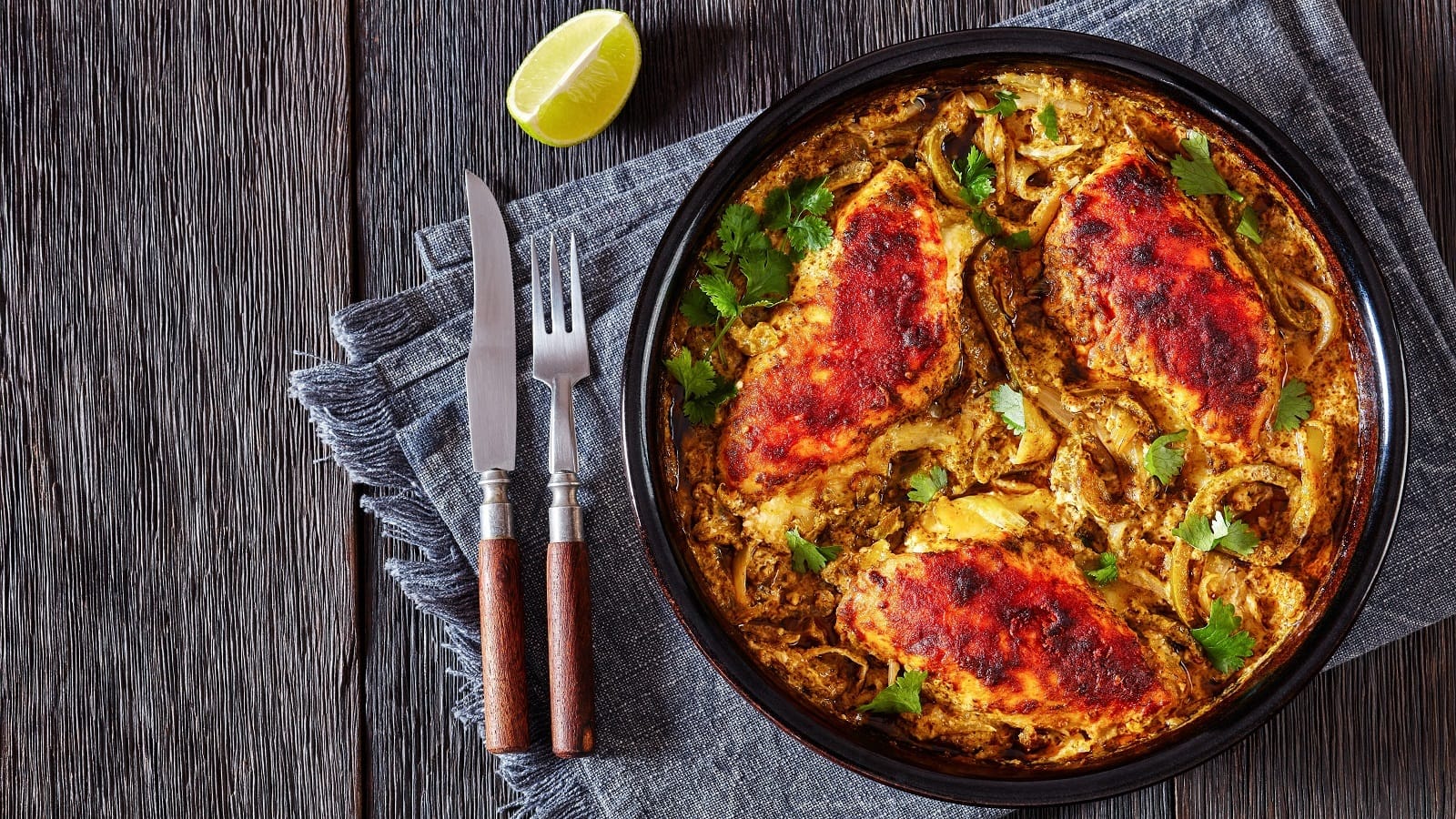 Ein Topf mit Salsa Verde Chicken auf einem blau-grauen Geschirrtuch auf einem Holztisch.