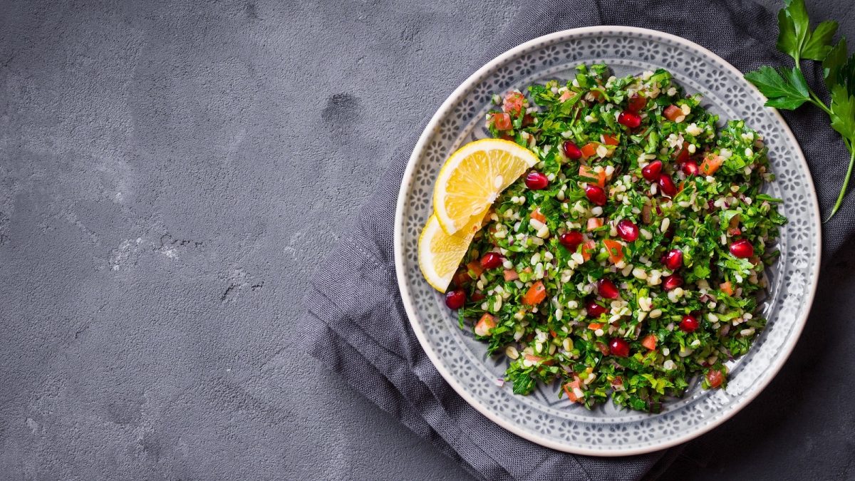 Ein Teller mit Tabouleh auf einem grauen Tisch.