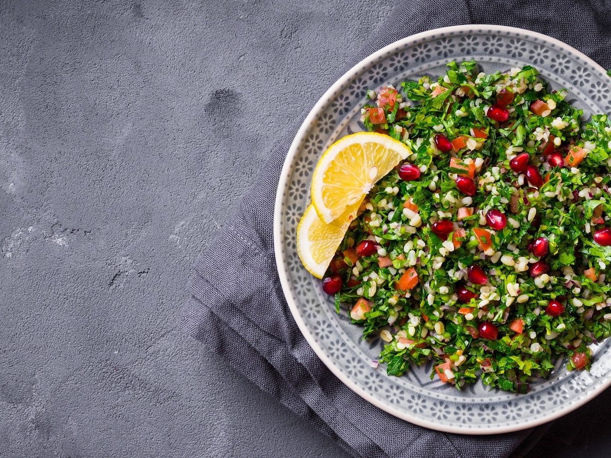 Ein Teller mit Tabouleh auf einem grauen Tisch.