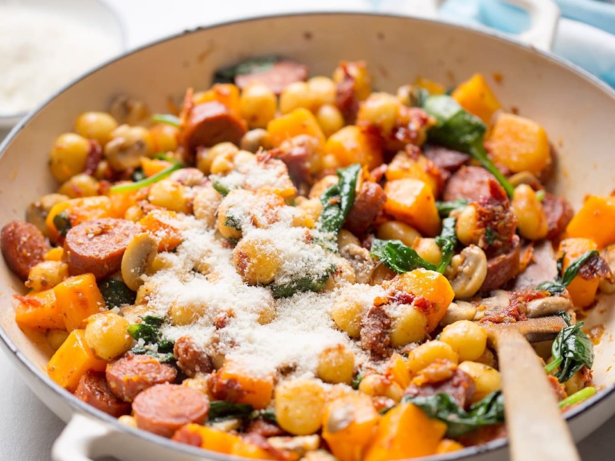 Eine weiße Pfanne mit den Gnocchi auf einem hellen Tisch mit einem blauen Tuch.