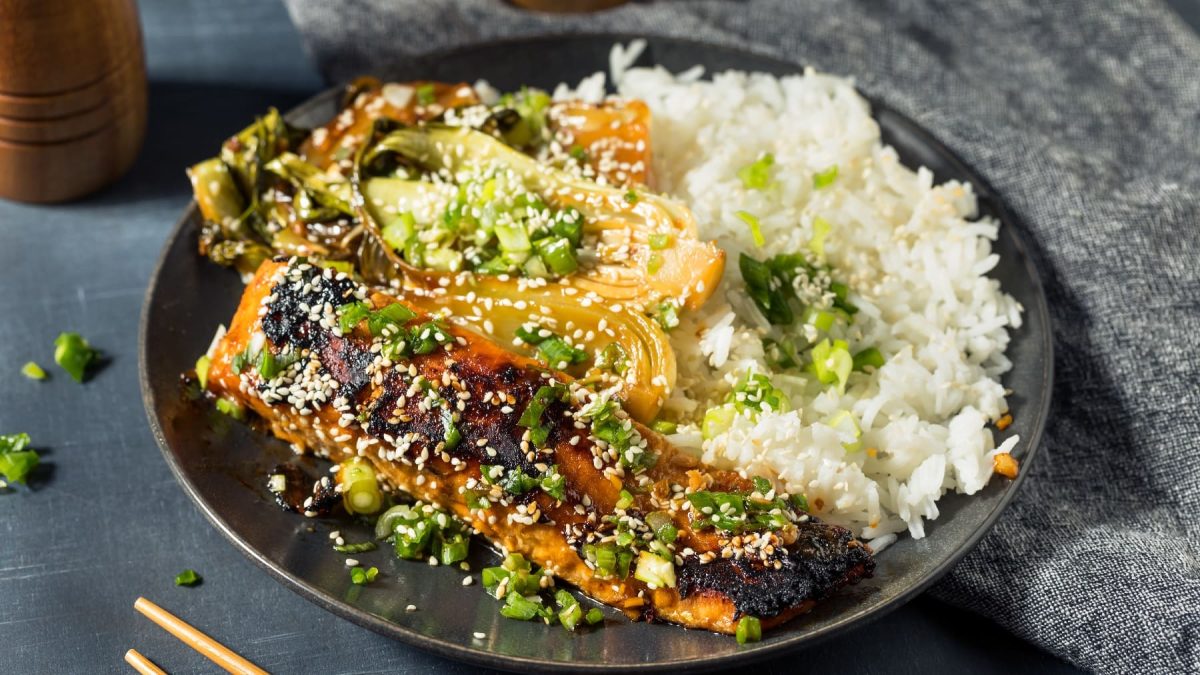 Ein schwarzer Teller mit dem Miso-Lachs auf einem dunkelgrauen Tisch.Miso-LAchs