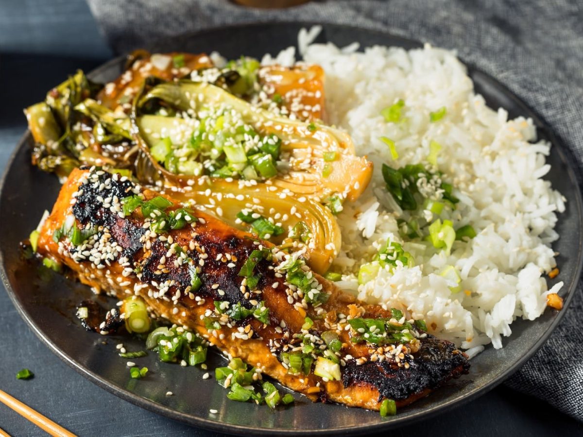 Ein schwarzer Teller mit dem Miso-Lachs auf einem dunkelgrauen Tisch.Miso-LAchs