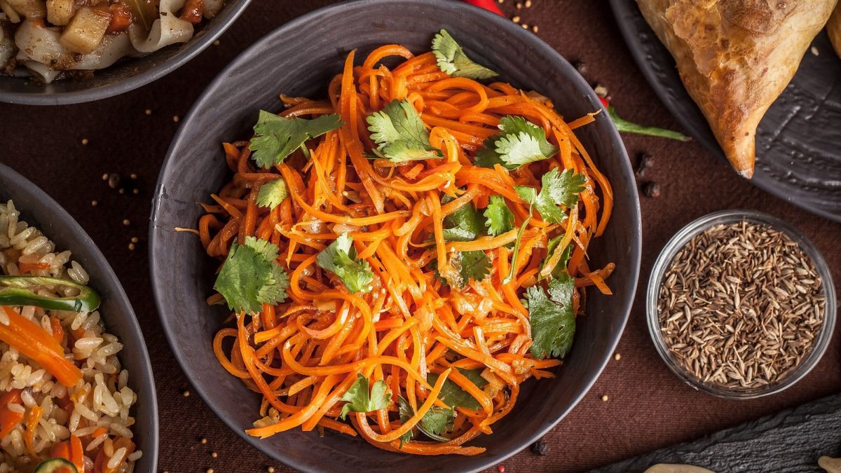 Ein Teller Morkowtscha, koreanischer Möhrensalat, mit Korianderblättern in der Draufsicht.