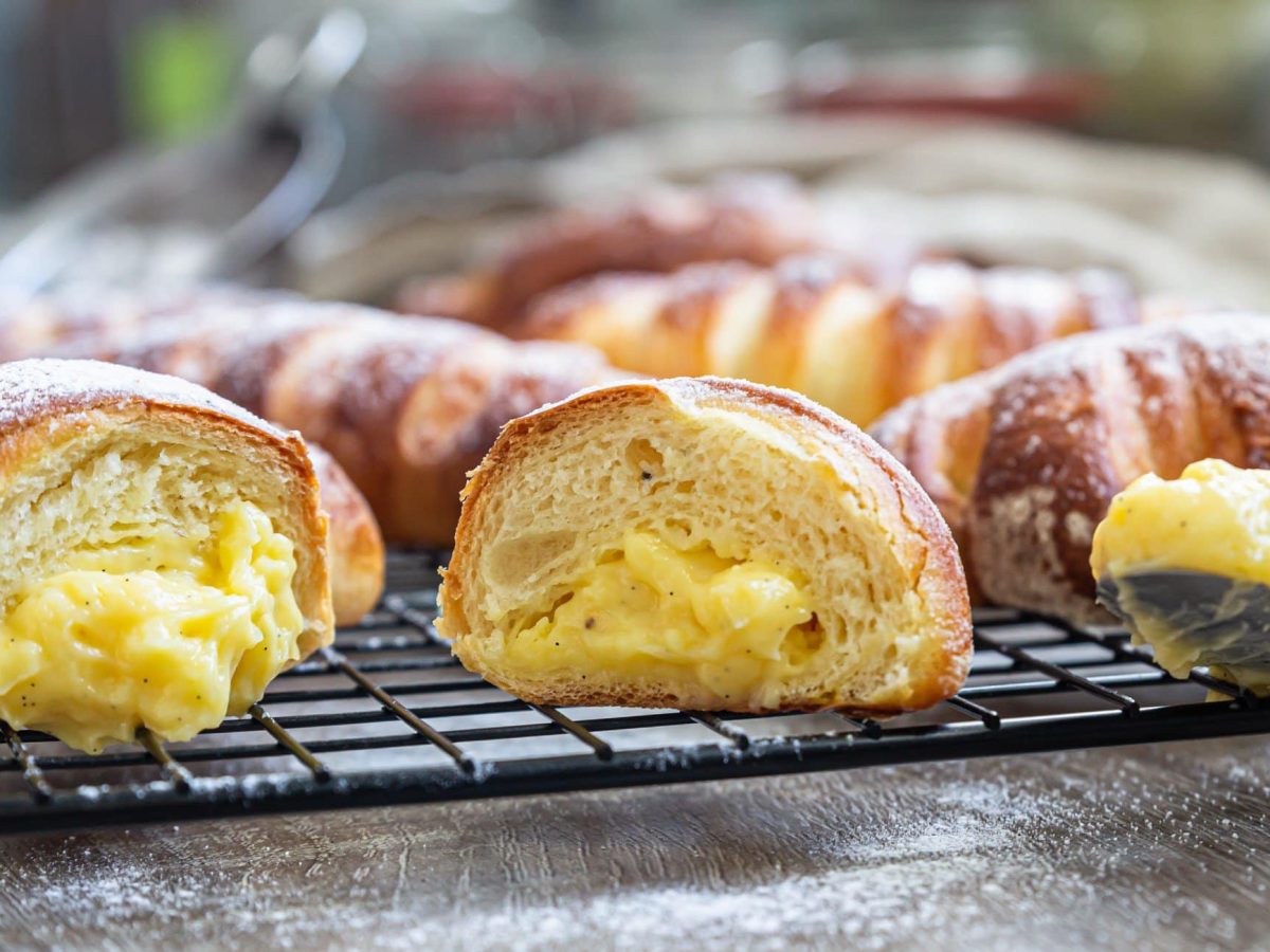 Selbst gemachte Brioche Pudding-Hörnchen auf Backrost. Frontalansicht.