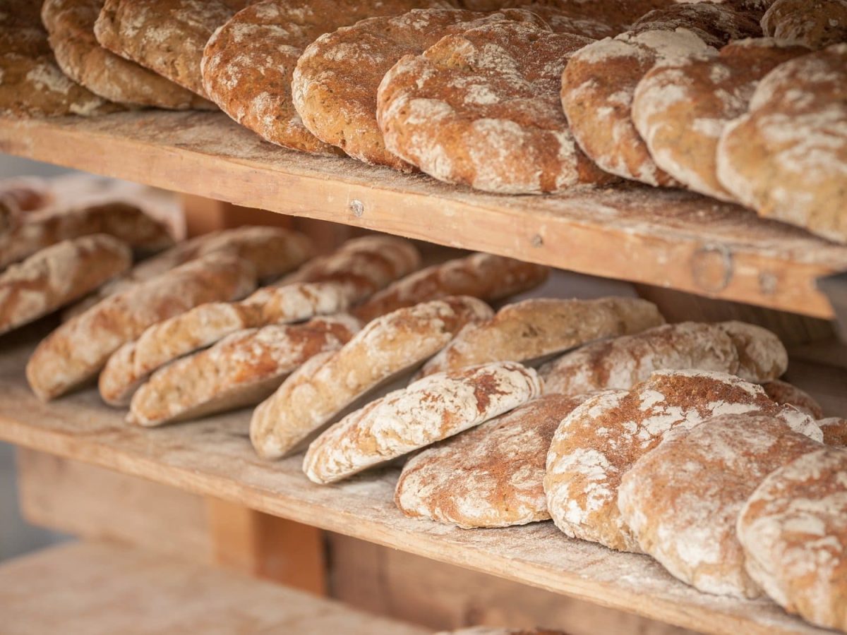 Frontalsicht: Ein Holzregal mit zwei Böden ist vollgepackt mit Brotfladen aus Südtirol. Dort nennt man sie vinschgauer.