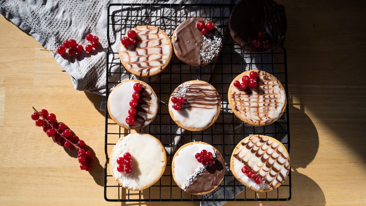 Ein Kuchengitter mit veganen Amerikanern in der Draufsicht, verziert mit Zuckerguss und Schokolade.