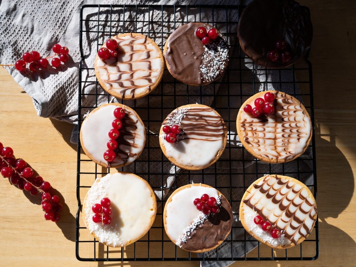 Ein Kuchengitter mit veganen Amerikanern in der Draufsicht, verziert mit Zuckerguss und Schokolade.