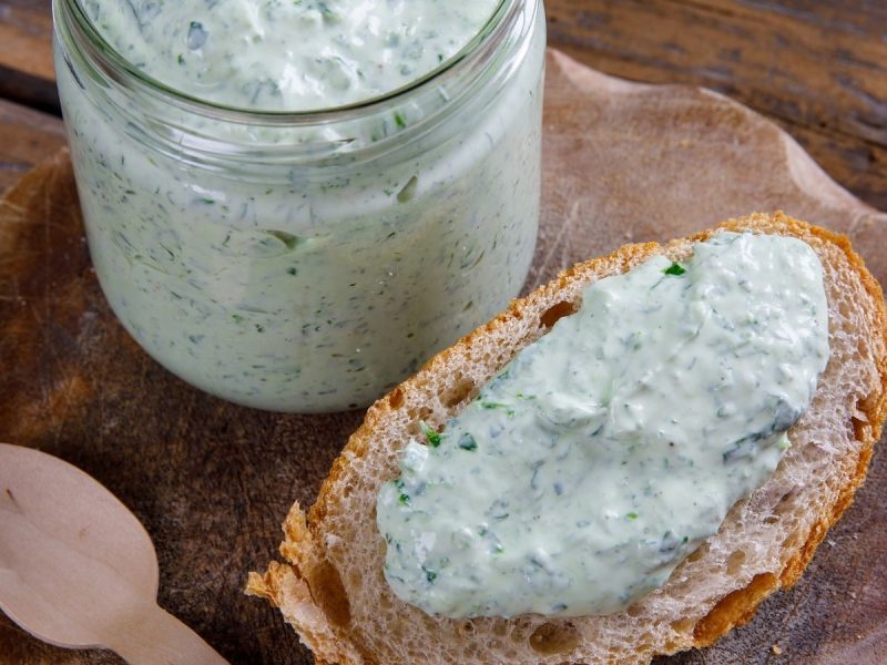 Eine Scheibe Brot mit Bärlauch-Aioli auf einem Holzbrett.