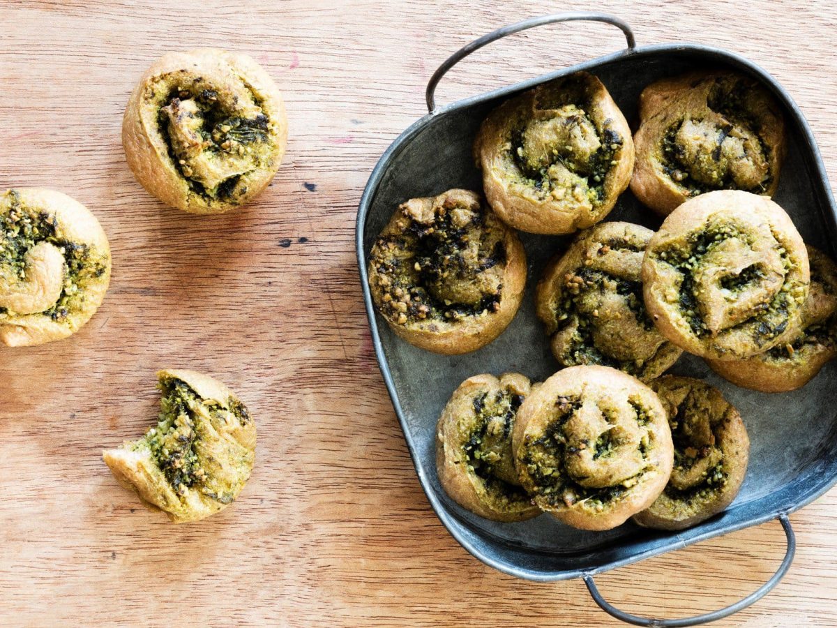 Bärlauch Pizza-Rolls in blauer Form auf Holz. Daneben weitere. Draufsicht.