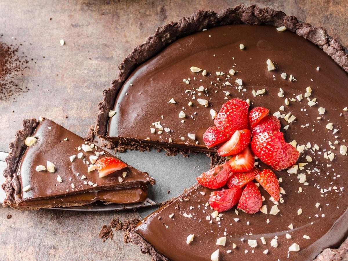 Eine angeschnittene Biscoff-Espresso-Tarte verziert mit Erdbeeren in der Draufsicht.