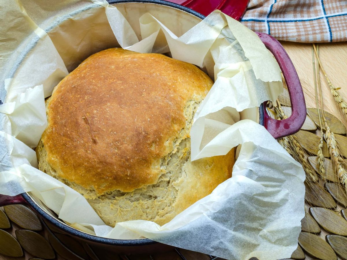 Crock-Pot Dinkel-Buttermilch-Brot ohne Hefe auf Tisch mit Ähren. Draufsicht.