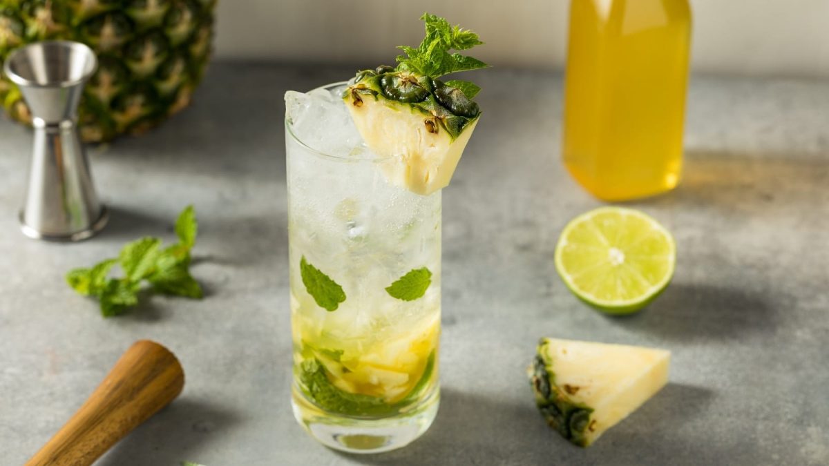 Ein Glas Ananas-Mojito auf einem grauen Tisch.