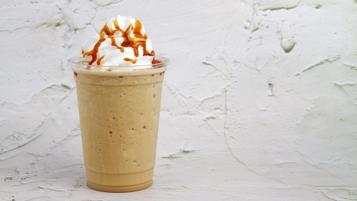 Ein Becher mit Biscoff Milkshake vor einem grauen Hintergrund.