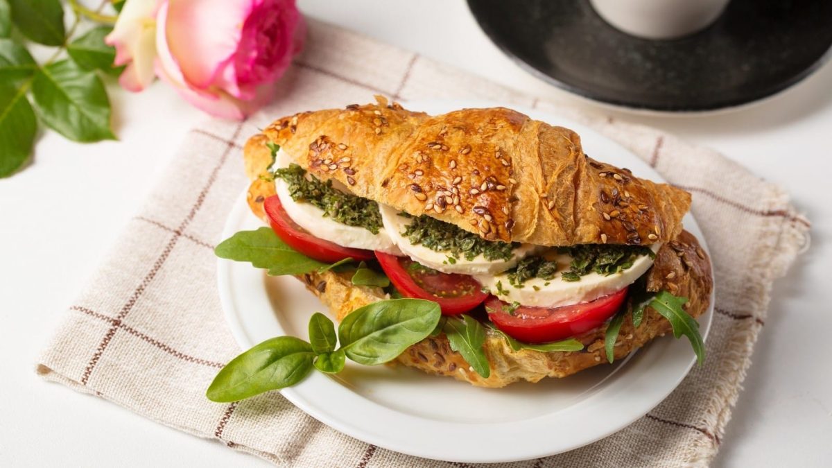 Ein Teller mit einem Caprese Croissant auf einem gestreiften Küchentuch.