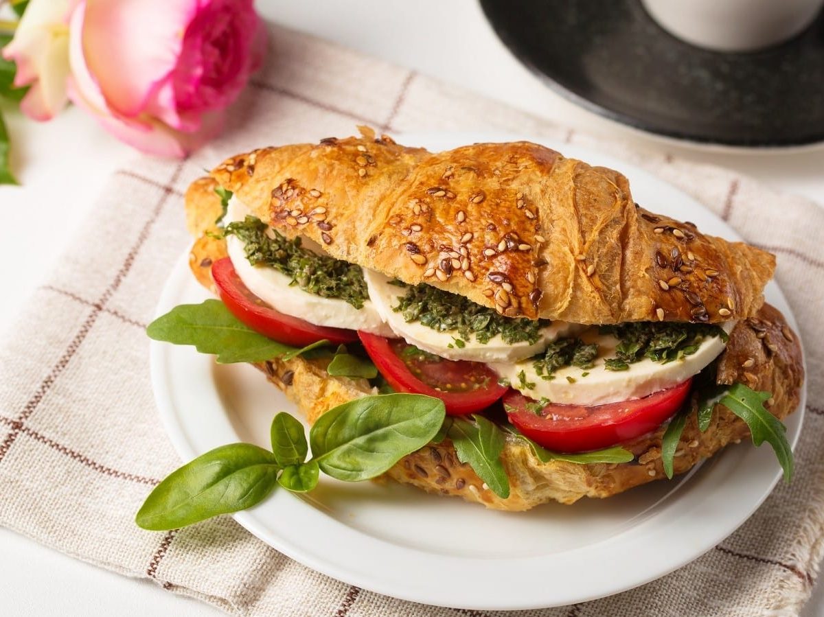 Ein Teller mit einem Caprese Croissant auf einem gestreiften Küchentuch.