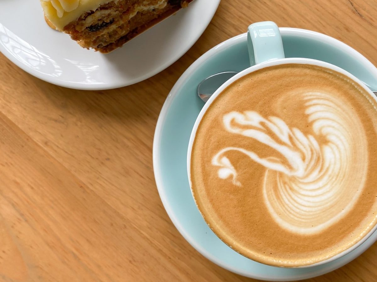 Eine hellblaue Tasse mit Carrot Cake Latte auf einem Holztisch.