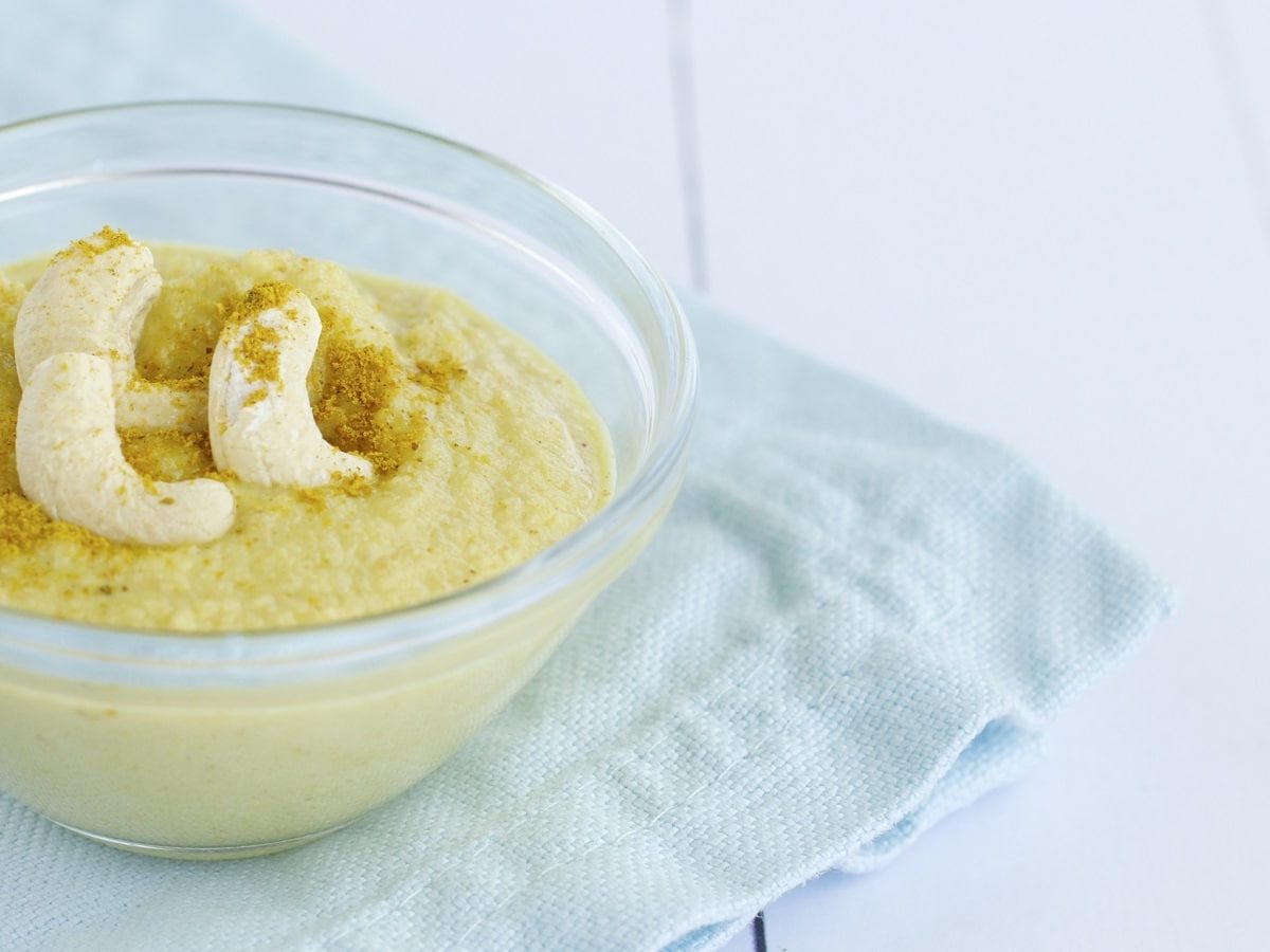 Eine Schüssel mit Cashew-Curry-Dip auf einem blauen Geschirrtuch.