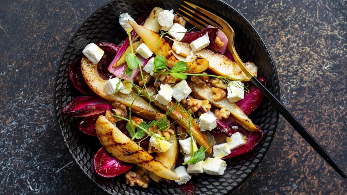 Eine schwarze Schüssel mit gebratenen Birnen mit Radicchio.