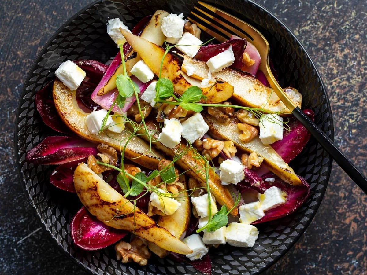 Eine schwarze Schüssel mit gebratenen Birnen mit Radicchio.