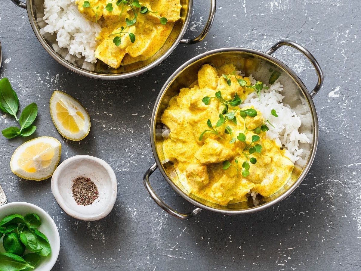 Eine Schüssel mit gelbem Lachs-Curry auf einem grauen Hintergrund.