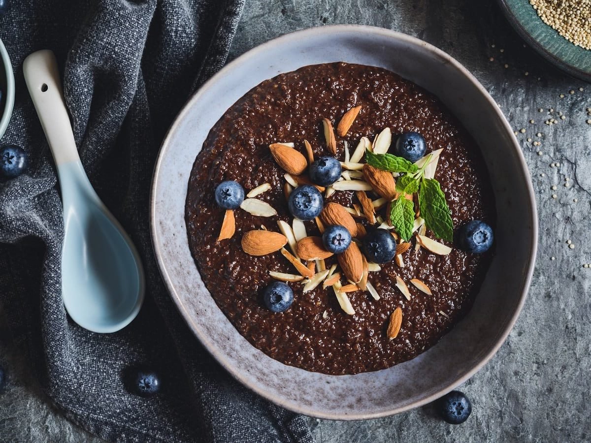 Eine Schüssel mit Kakao-Quinoa-Porridge auf grauem Tisch.