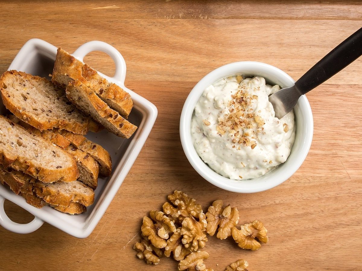 Eine kleine Schüssel mit Knoblauch-Walnuss-Dip auf einem Holzbrett.