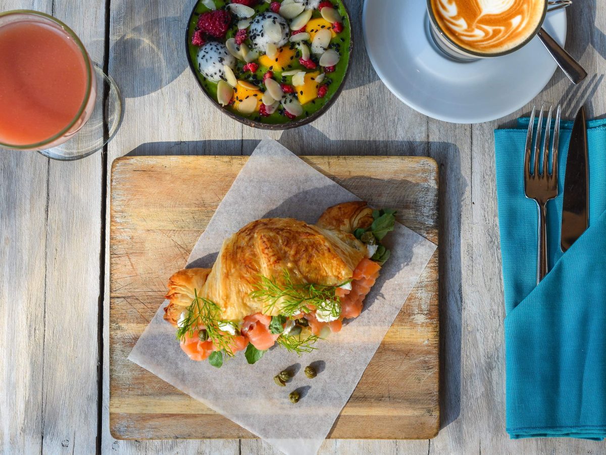 Ein Teller mit gefülltem Lachs-Croissant auf einem gedeckten Frühstückstisch.