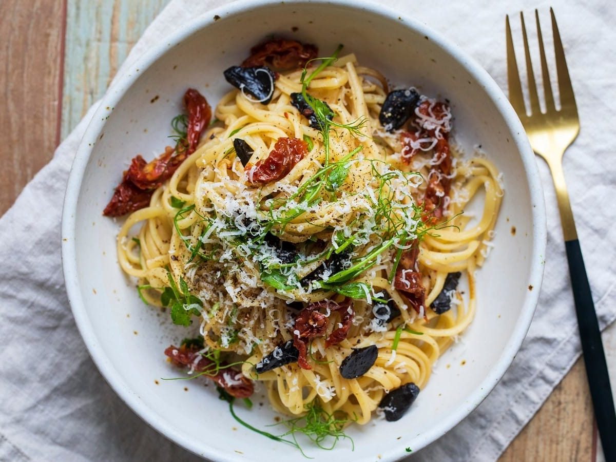 Ein runder Teller mit Pasta mit schwarzem Knoblauch.