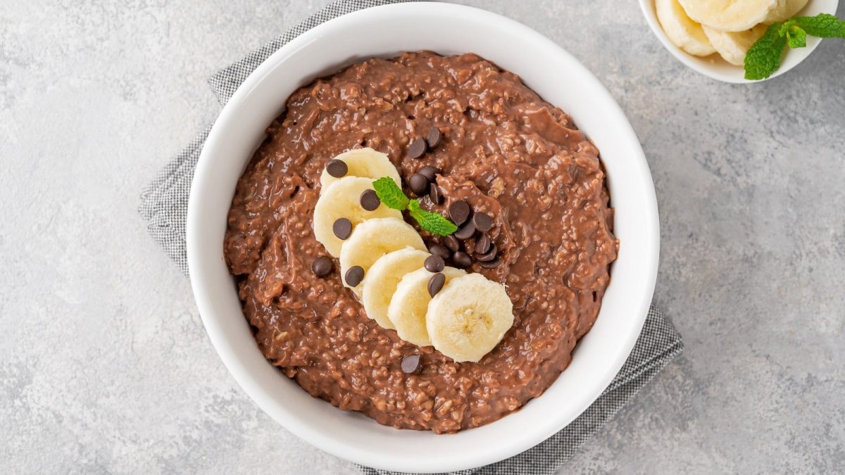 Eine runde weiße Schüssel mit Mocha Overnight Oats auf einem grauen Tisch.