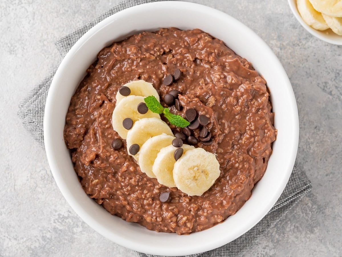 Eine runde weiße Schüssel mit Mocha Overnight Oats auf einem grauen Tisch.