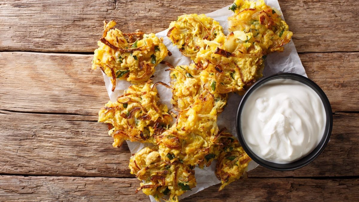 Ein Tablett mit Onion Bhaji auf einem Holztisch.