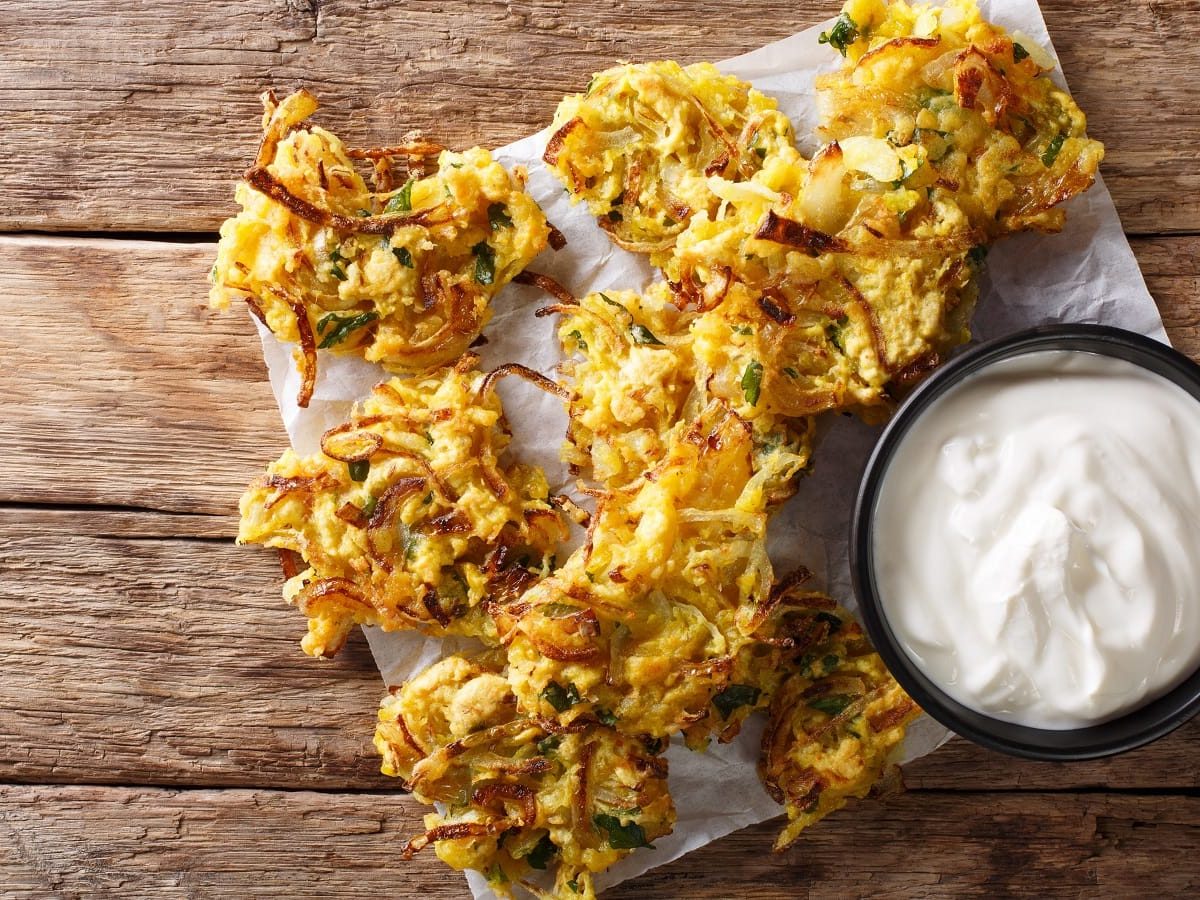 Ein Tablett mit Onion Bhaji auf einem Holztisch.