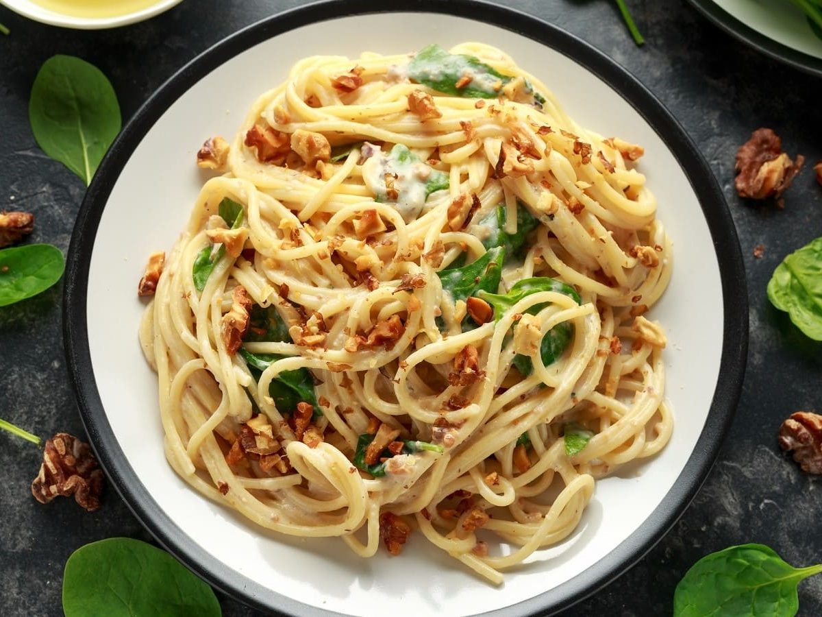 Ein Teller mit Pasta mit Walnussbutter auf einem dunkelgrauen Tisch.